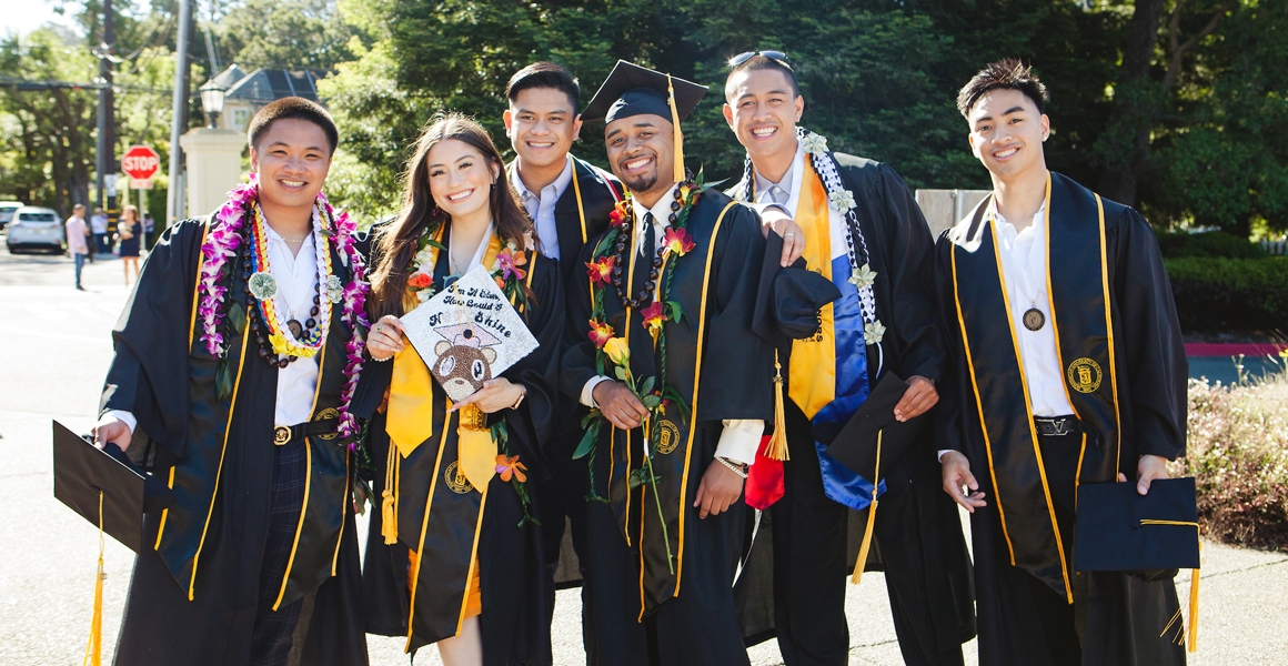 a group of ֱ University of California students posing in regalia at their graduation 