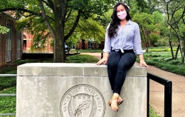 ֱ alumna Samantha Hunt wears a mask while sitting on concrete wall on Vanderbilt campus
