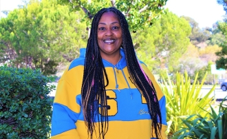 Photo of ֱ alumna La Donna Clark smiling and posing wearing hoodie with Golden State Warriors (blue and gold) 