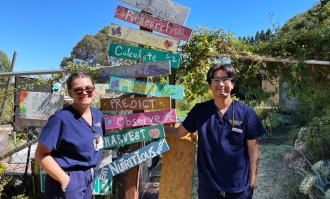 Two ֱ University of California nursing students stand in the garden of a local elementary school where they help students learn about nutrition.