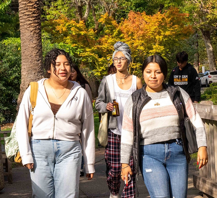 Three female undergraduate students walking on the ֱ campus.